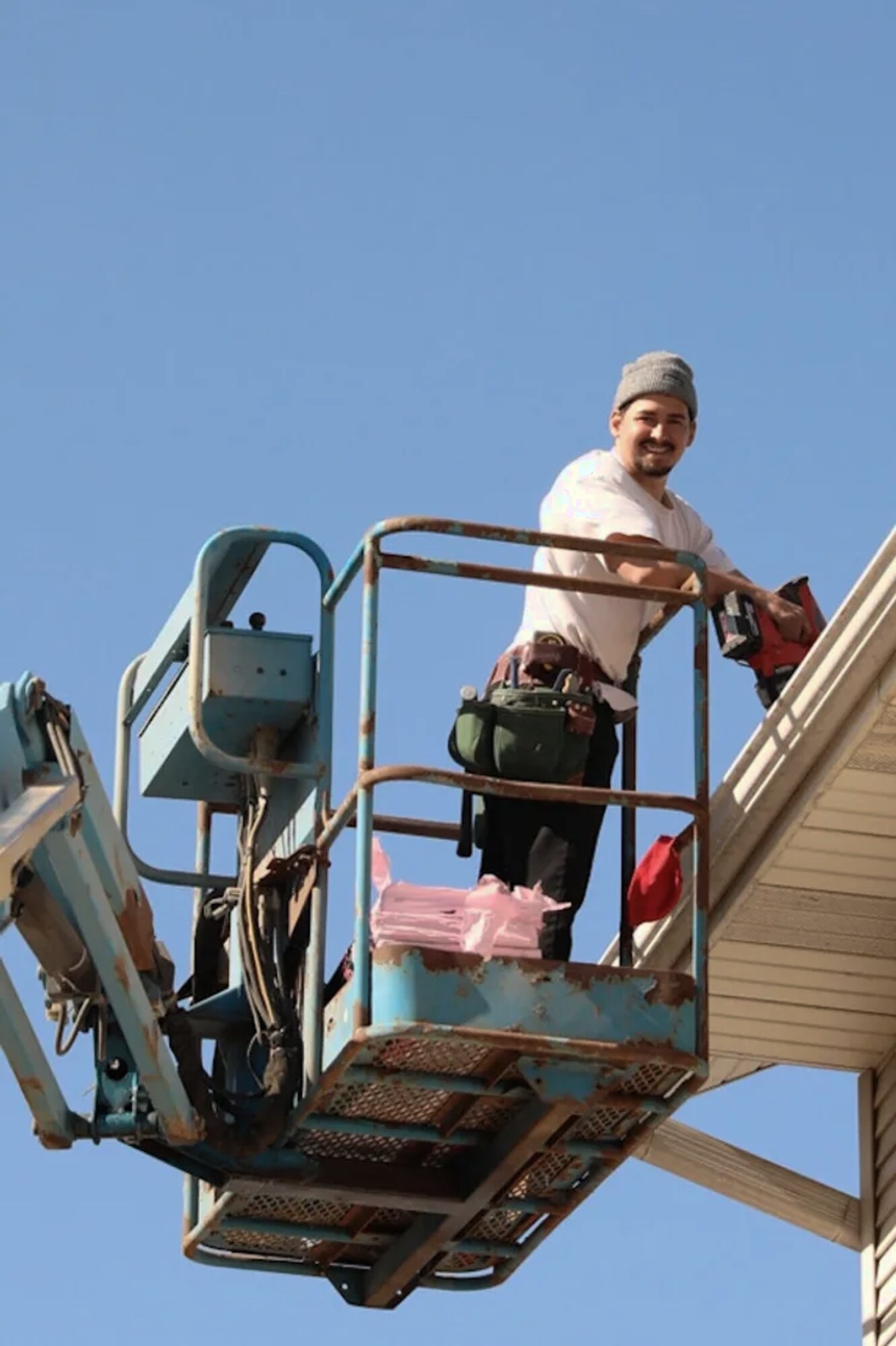 Aaron Lambright, owner of Prime Time Roofing & Construction, working on a lift beside a roofline